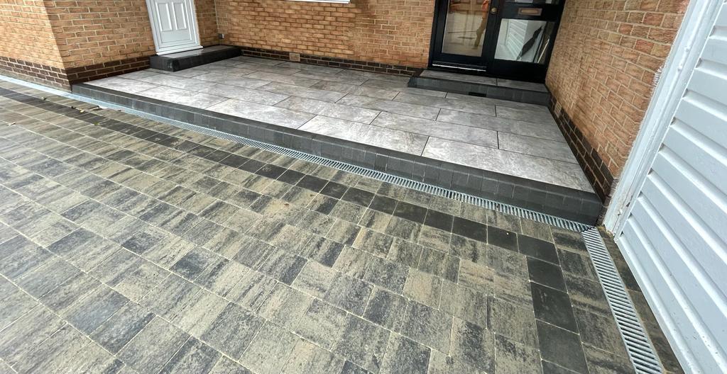 Channel drain running across a porcelain entrance area at a door threshold — The Vale Company