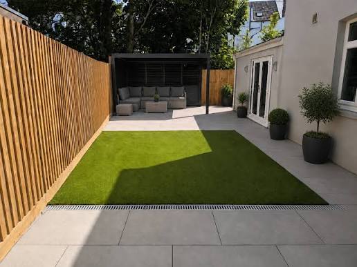 Artificial grass lawn set into a large-format porcelain courtyard with a slot drain along its front edge — The Vale Company