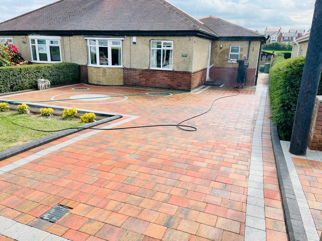 Wide autumn red block paved driveway with a circular feature and a contrasting soldier course — The Vale Company