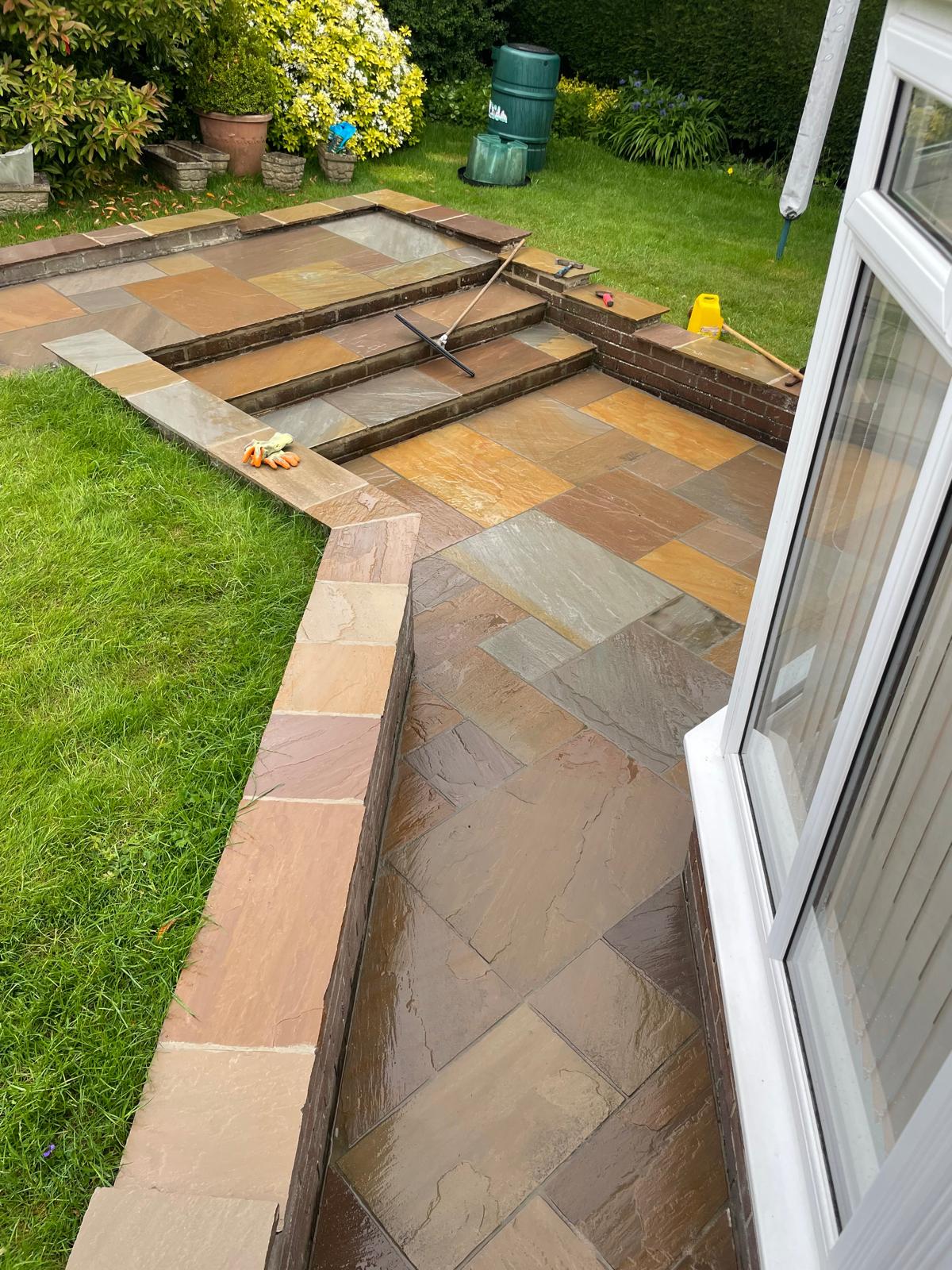 Autumn blend Indian sandstone patio with brick-edged steps to a raised terrace — The Vale Company