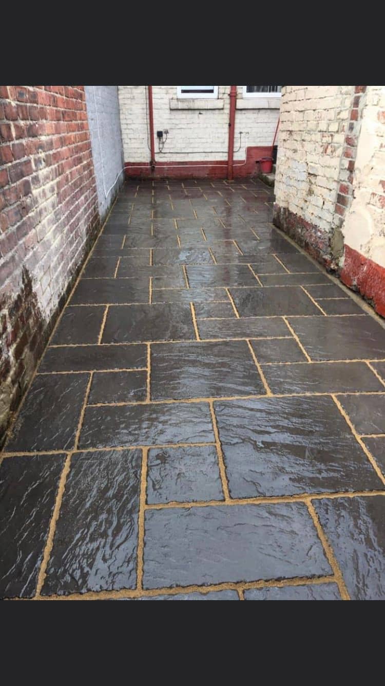 Black limestone paving laid through a narrow courtyard with buff jointing — The Vale Company