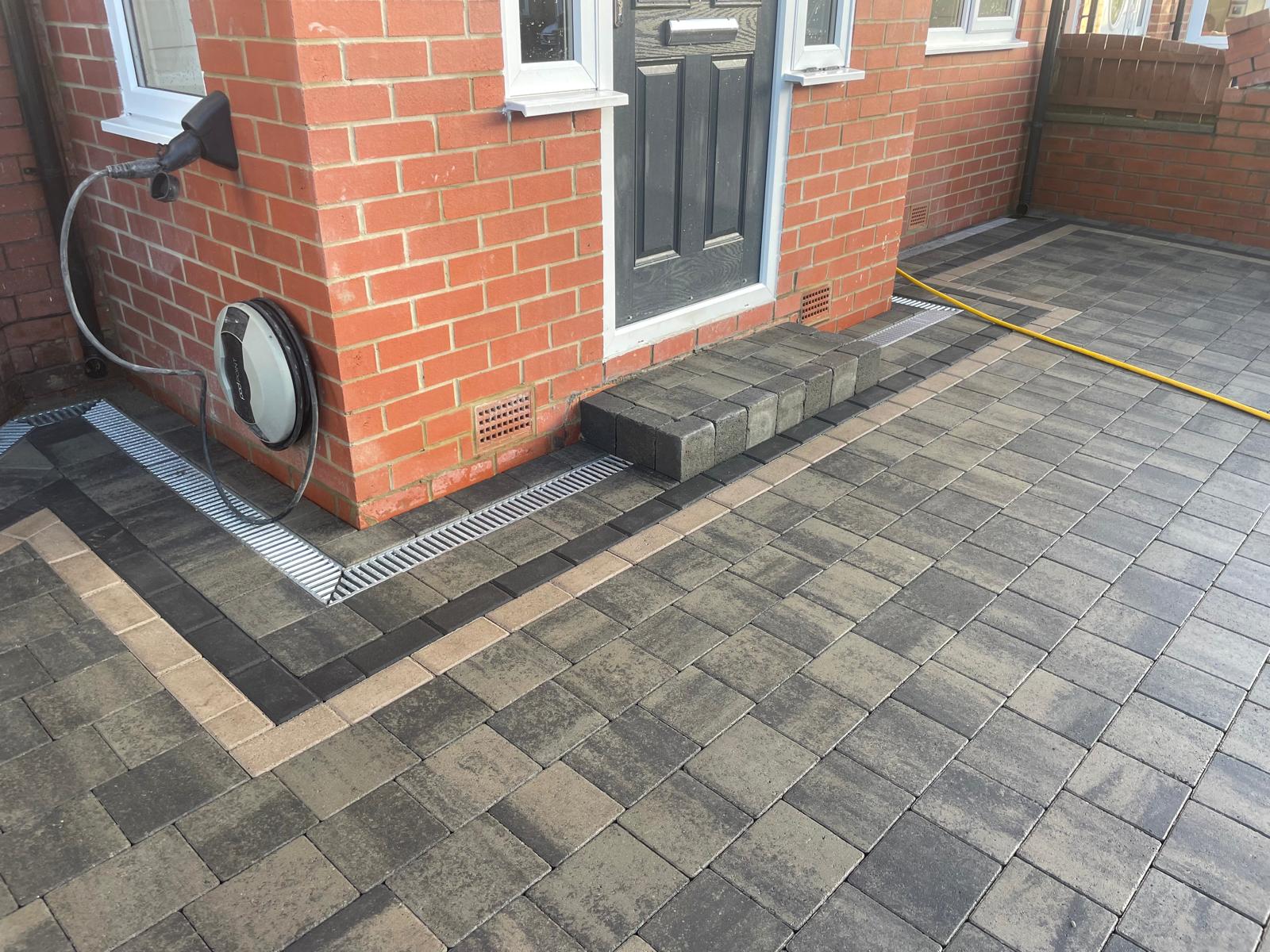 Block paved driveway cut neatly around a wall-mounted EV charge point — The Vale Company