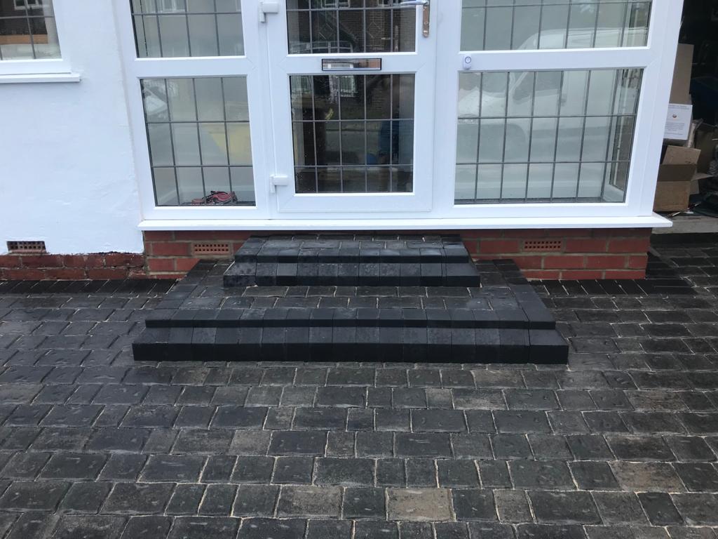Charcoal block steps built up to a conservatory door off a block paved drive — The Vale Company