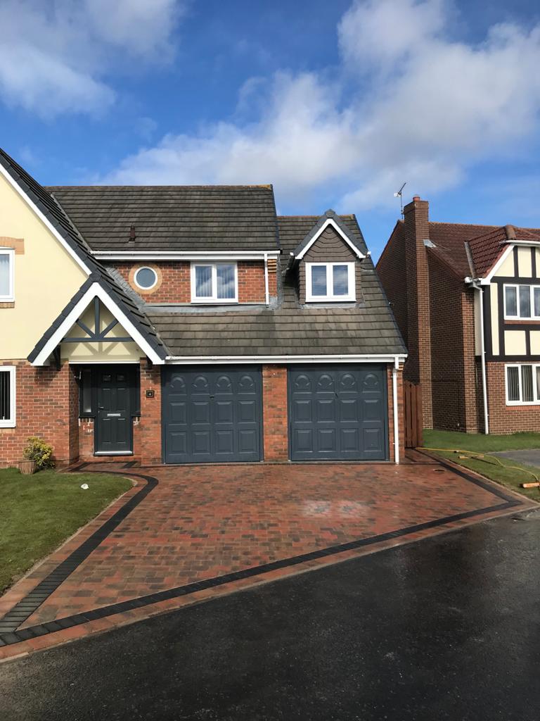 Brindle block paved driveway with a charcoal border running to a double garage — The Vale Company