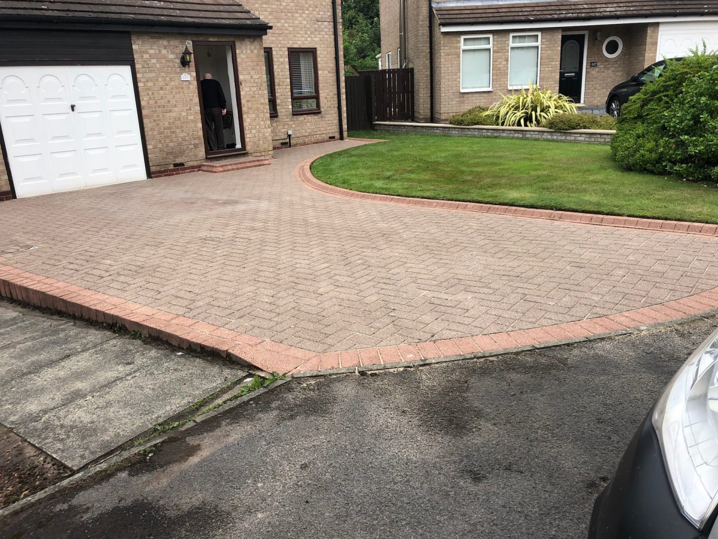 Buff block paved driveway with a red block border sweeping in a curve around a lawn — The Vale Company