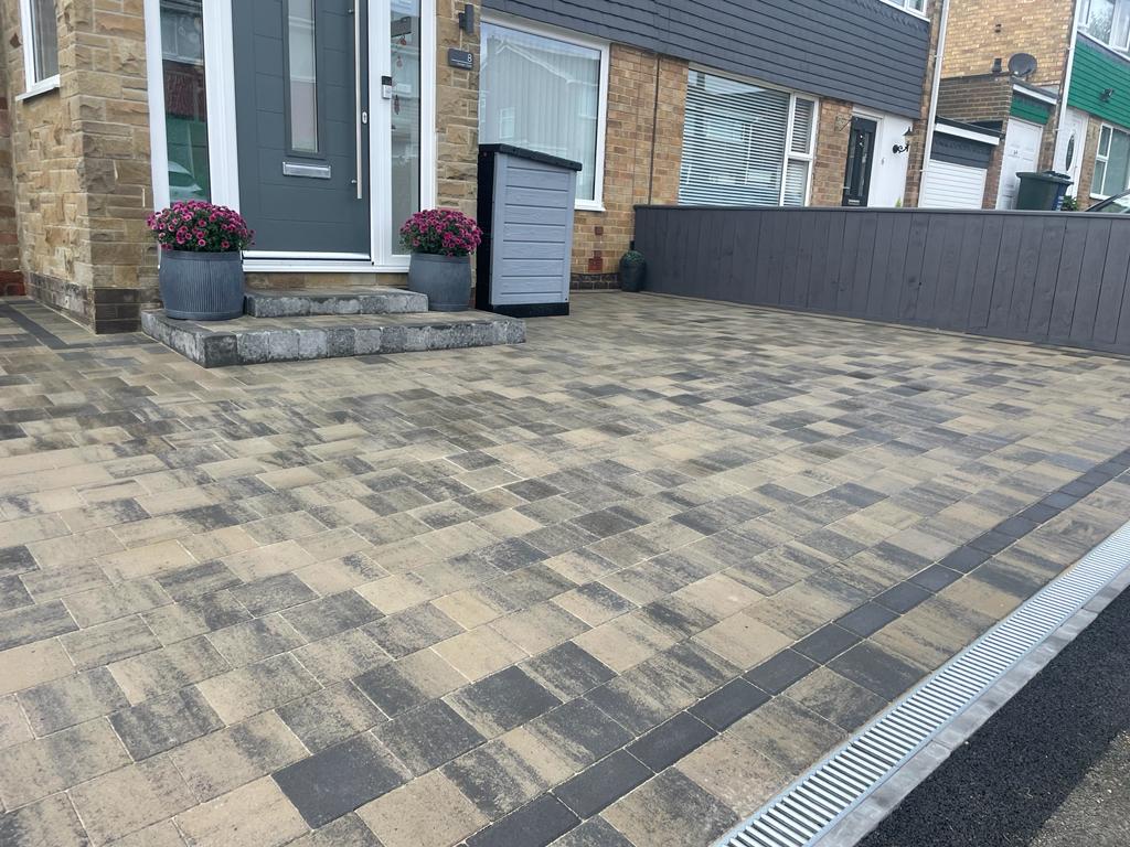Linear channel drain set flush across a driveway at the road edge — The Vale Company