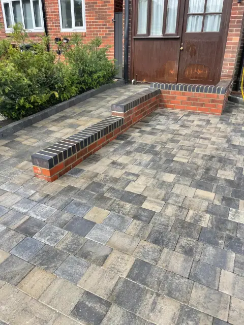 Full-width charcoal tumbled block driveway with a contrasting border — The Vale Company