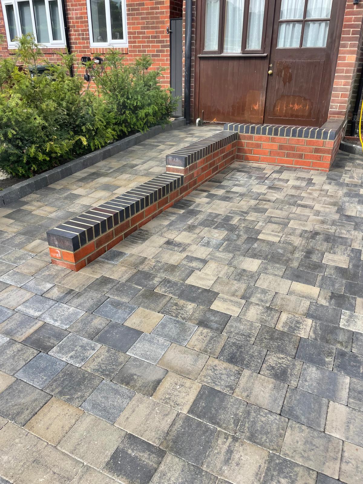 Full-width charcoal tumbled block driveway with a contrasting border — The Vale Company
