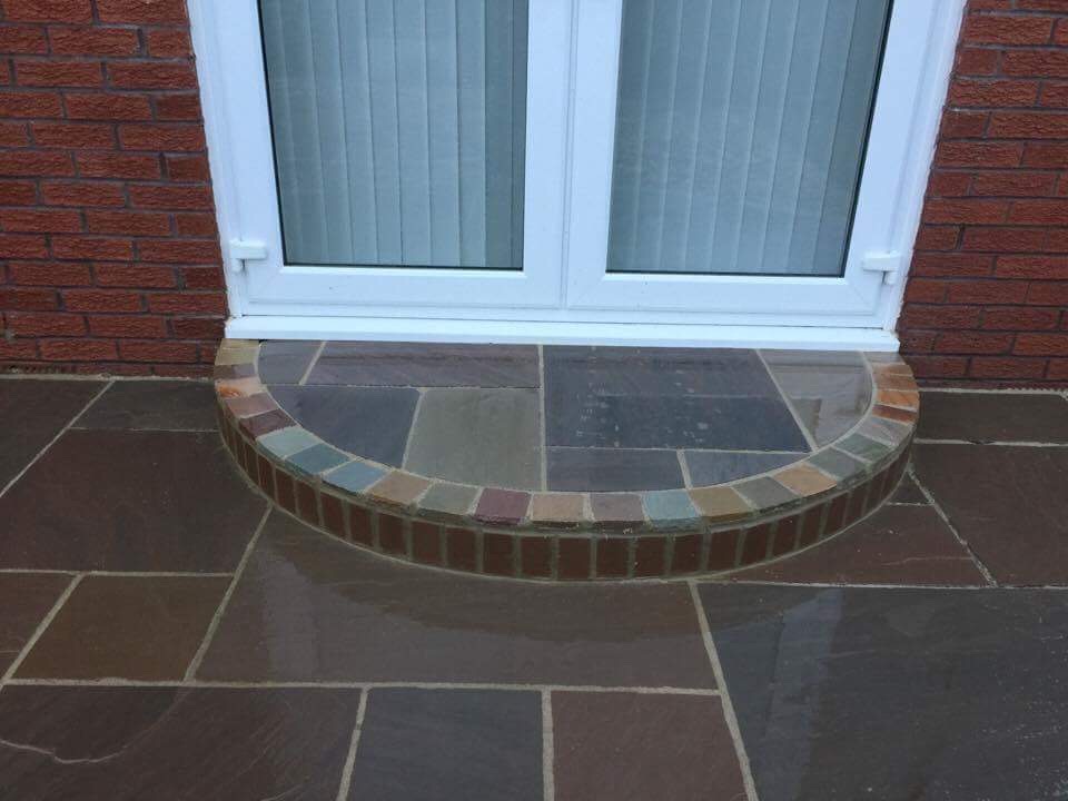 Curved brick-edged sandstone step built up to patio doors — The Vale Company