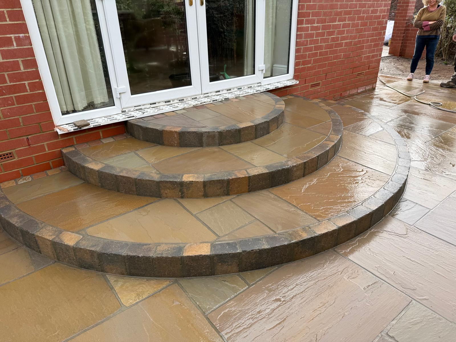 Two curved sandstone steps with brindle block risers at a set of patio doors — The Vale Company