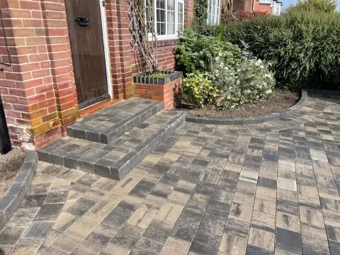 Curved block paved driveway with radius block edging sweeping around a planting bed — The Vale Company