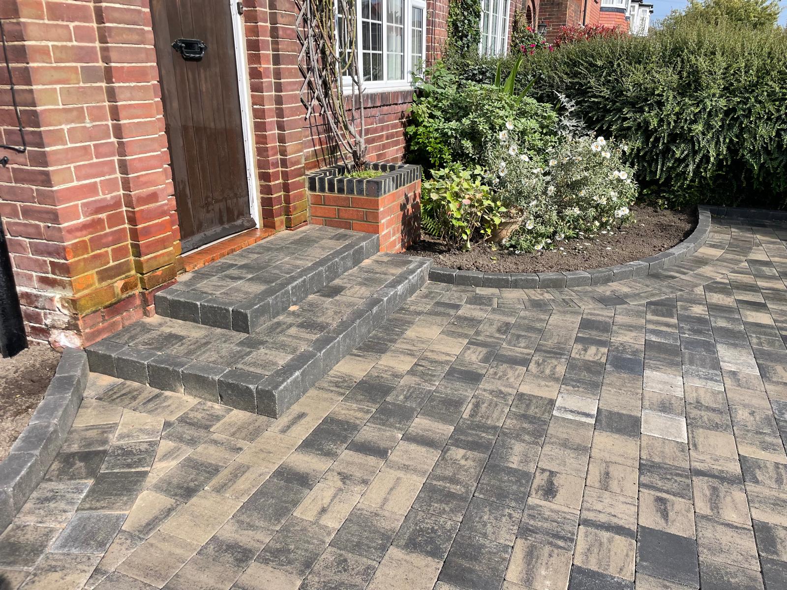 Curved block paved driveway with radius block edging sweeping around a planting bed — The Vale Company