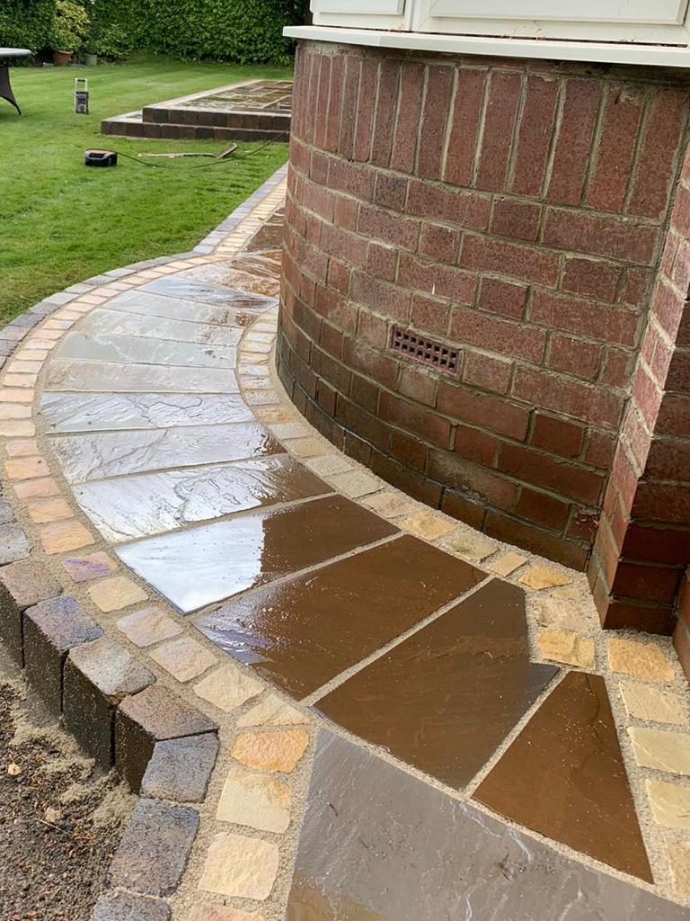 Curved Indian sandstone path with a tumbled sett border sweeping around a curved bay wall — The Vale Company