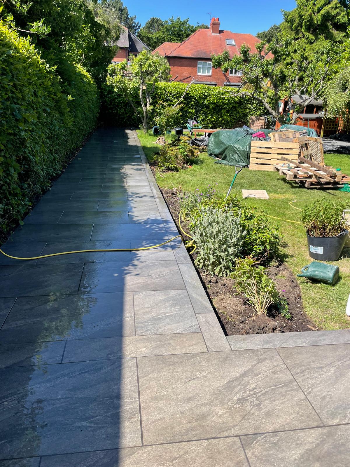 Long dark grey porcelain path with a contrasting border running alongside a new planting bed — The Vale Company