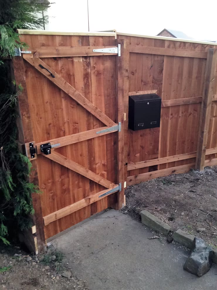 Feather-edge gate on a braced frame with galvanised strap hinges and a lock, hung against matching close-board fencing — The Vale Company