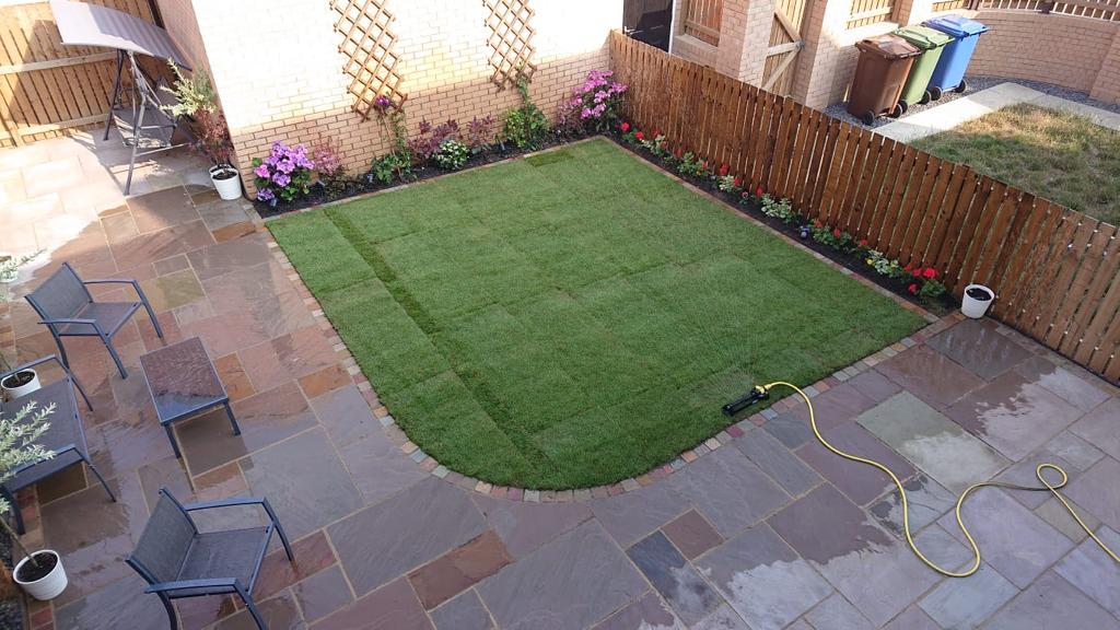 Full garden build with sandstone paving wrapping around new turf edged in setts — The Vale Company