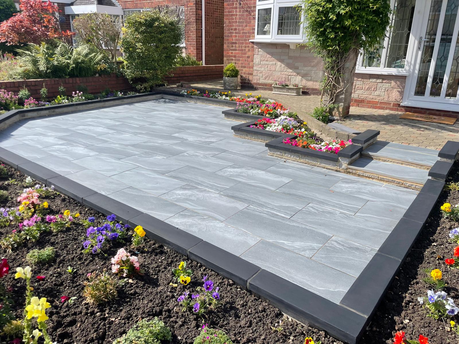 Grey veined porcelain front garden terrace with charcoal coping edging and planting beds — The Vale Company