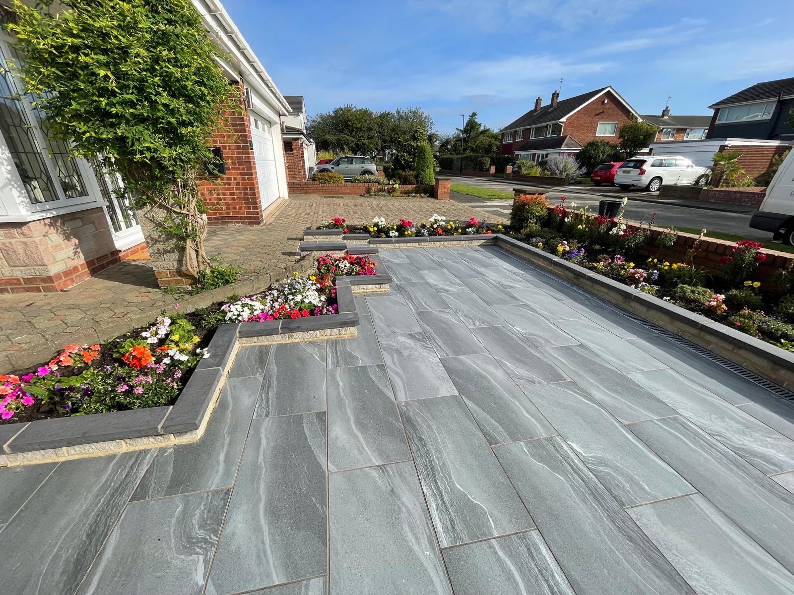 Grey porcelain front terrace bounded by charcoal-coped raised beds — The Vale Company