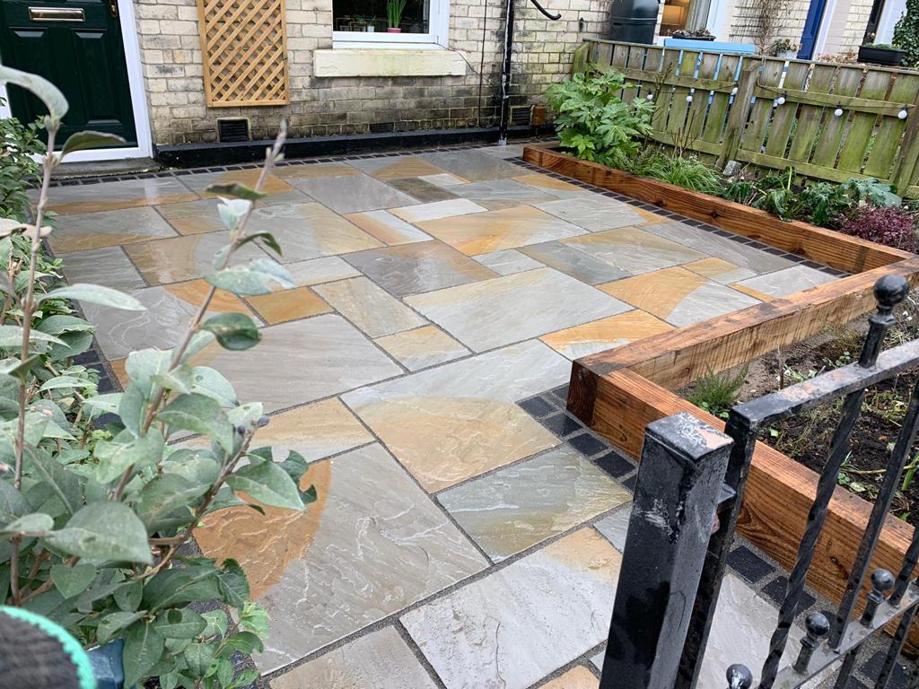 Random-coursed grey Indian sandstone patio with charcoal block edging — The Vale Company