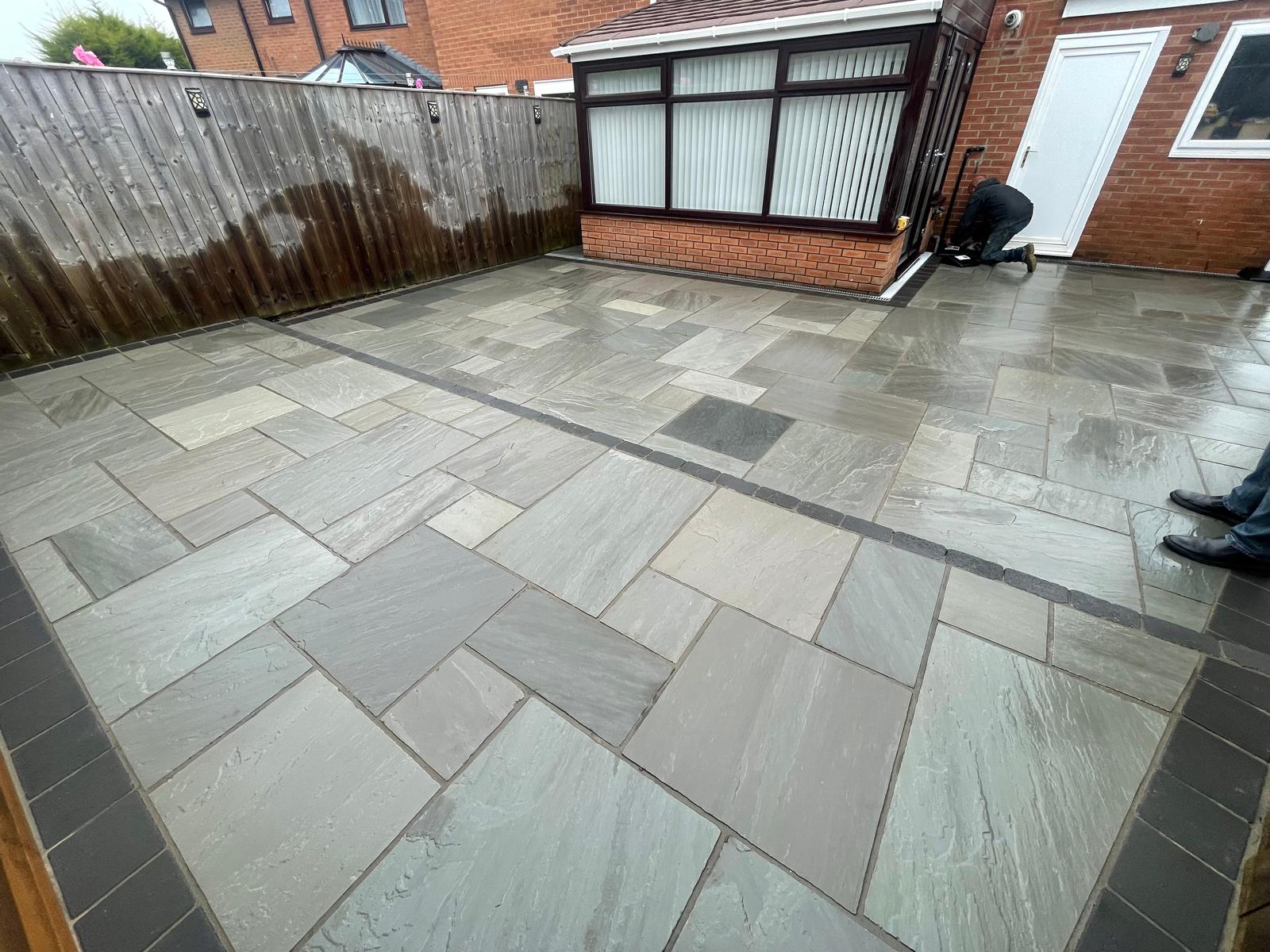 Wide grey Indian sandstone patio with charcoal sett banding across the middle — The Vale Company