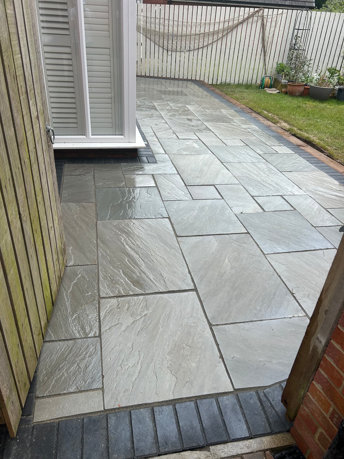Grey Indian sandstone side terrace edged with a charcoal block soldier course — The Vale Company