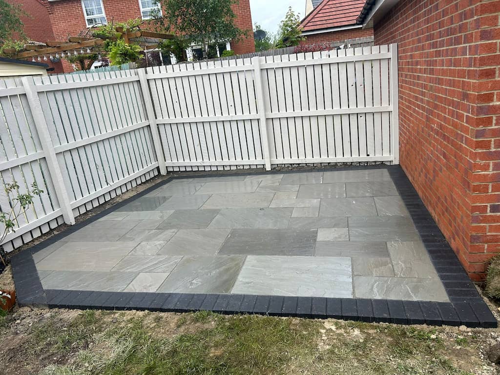 Square grey Indian sandstone patio framed by a charcoal block soldier course border — The Vale Company