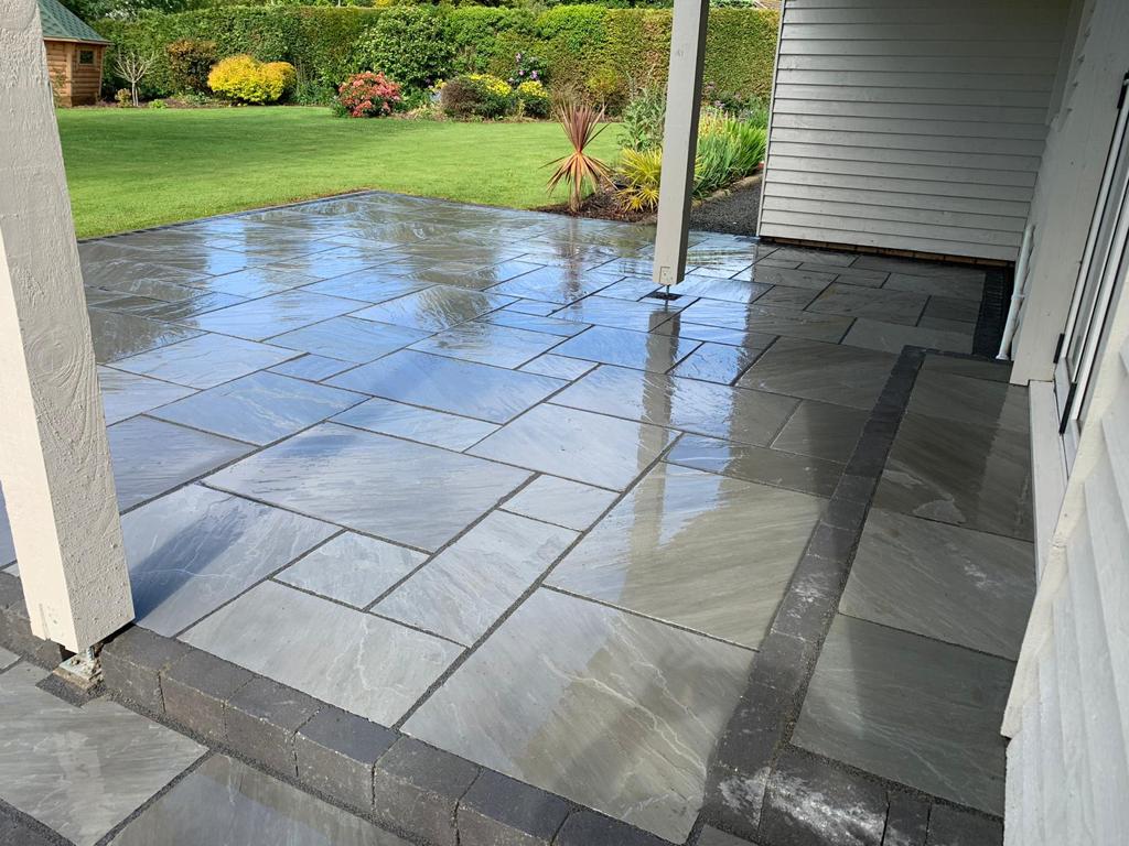 Grey Indian sandstone paving under a veranda with a charcoal sett border and banding — The Vale Company