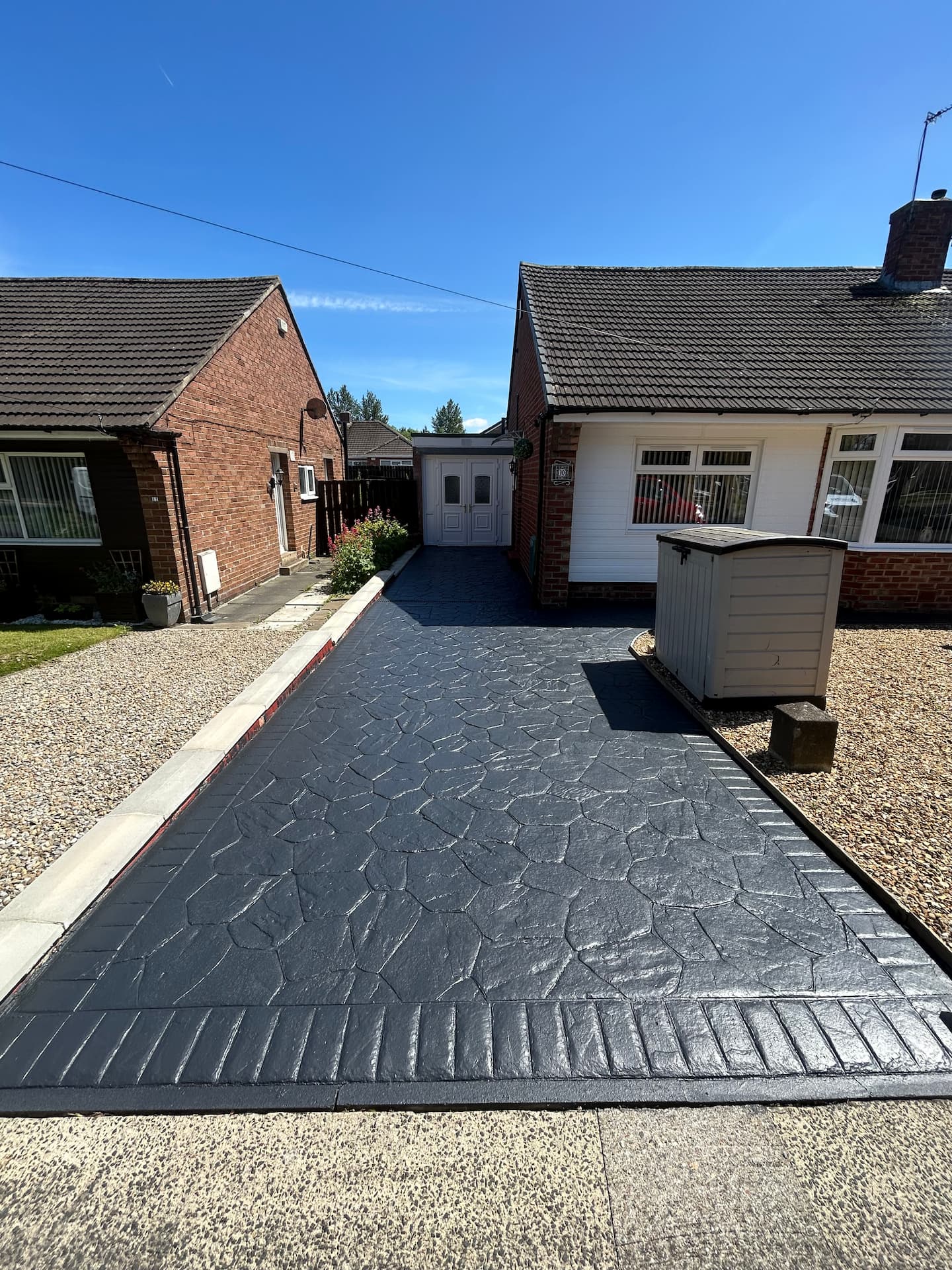 Charcoal pattern imprinted concrete driveway with a slate texture and a brick-pattern border — The Vale Company