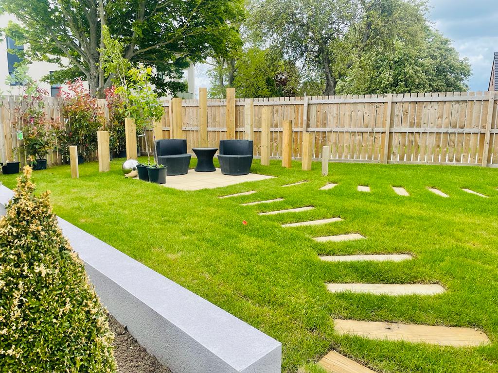 New turf with stepping stones set flush into the lawn and a granite kerb edge to the border — The Vale Company