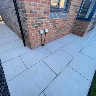 Light grey large-format porcelain wrapping around the corner of a house to the lawn edge — The Vale Company