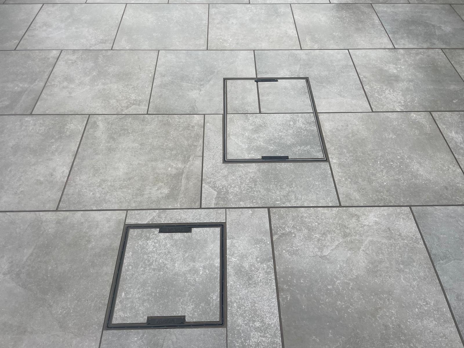 Two recessed manhole covers infilled with matching grey porcelain — The Vale Company