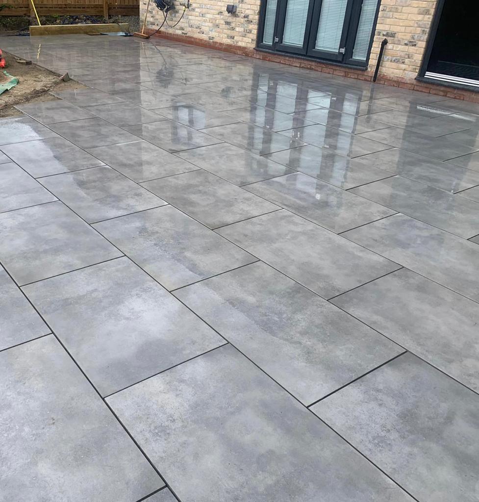 Wet grey large-format porcelain terrace laid to a fall away from the house — The Vale Company