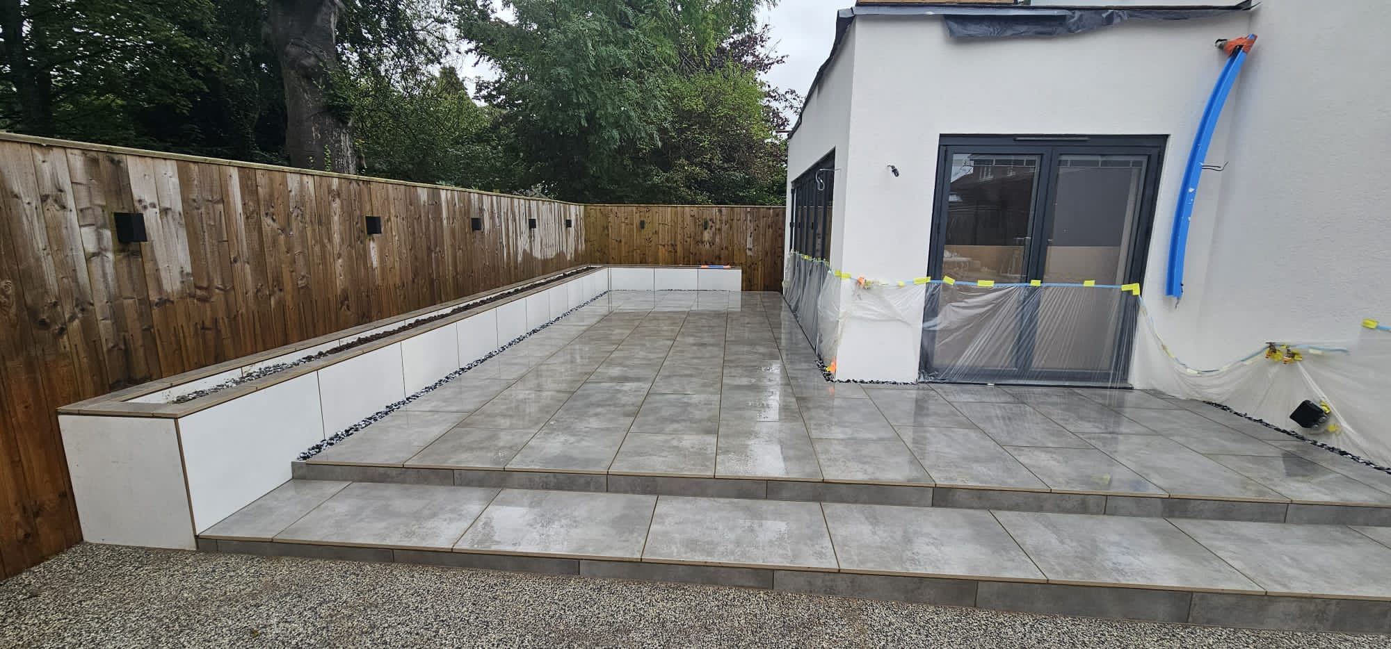 Porcelain terrace and steps with a tile-clad raised planter and a gravel drainage strip at the walls — The Vale Company