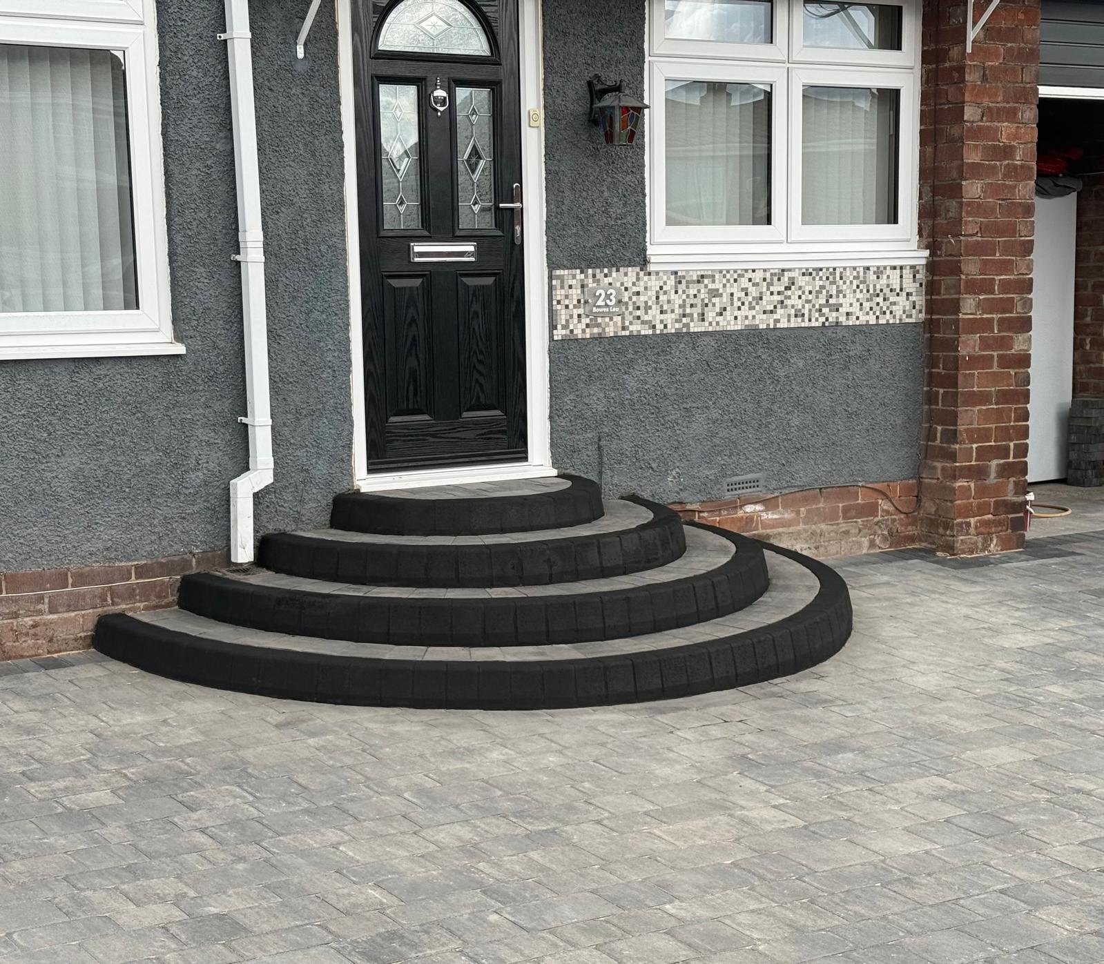 Radius entrance steps in block with charcoal bullnose edging sweeping onto a block drive — The Vale Company