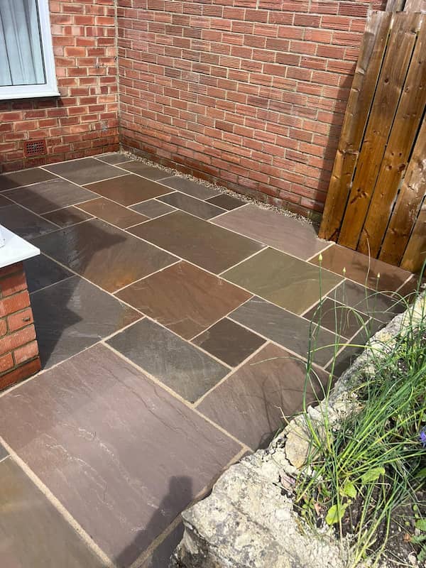 Multi-tone raj sandstone laid in a small courtyard with a gravel margin at the wall — The Vale Company
