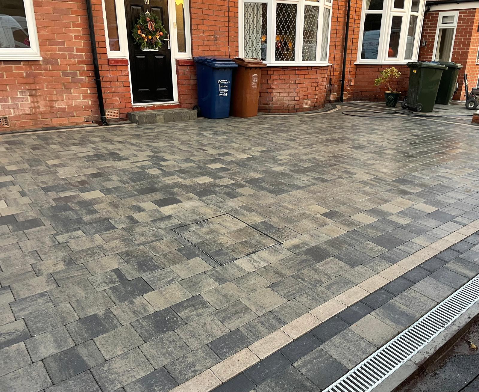 Recessed inspection cover cut into a block paved driveway so it reads as part of the pattern — The Vale Company