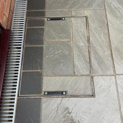 Recessed manhole cover infilled with cut Indian sandstone beside a channel drain — The Vale Company