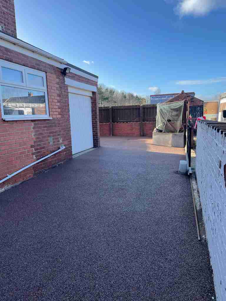 After: resin bound surfacing laid across a gated yard up to the garage door — The Vale Company