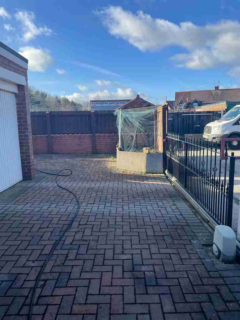 Before: worn and settled block paving across a gated yard ahead of resurfacing — The Vale Company