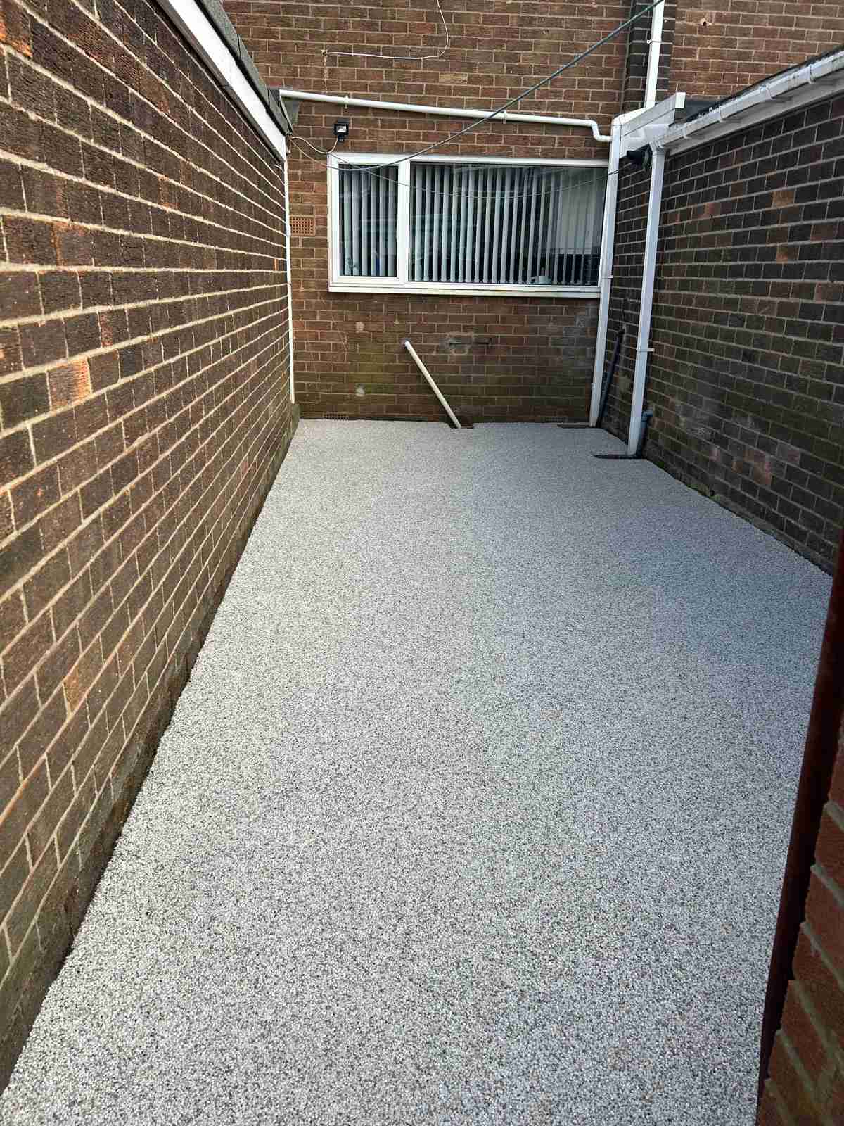 After: pale resin bound surfacing laid seamlessly through a narrow side yard — The Vale Company