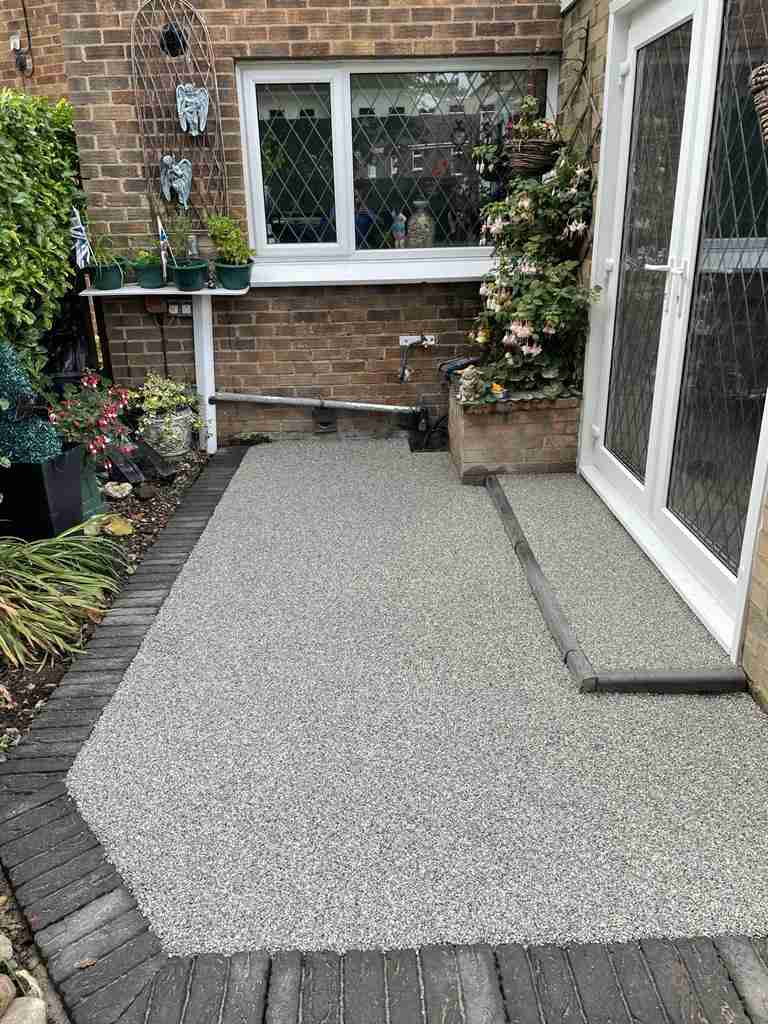 After: silver resin bound patio laid to a channel drain running back from the doors — The Vale Company
