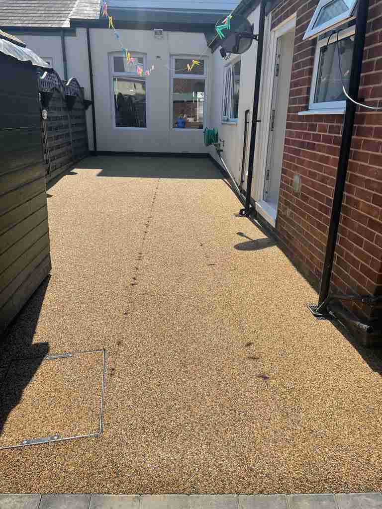 After: gold resin bound yard laid flush with a recessed cover tray and kerb edge — The Vale Company