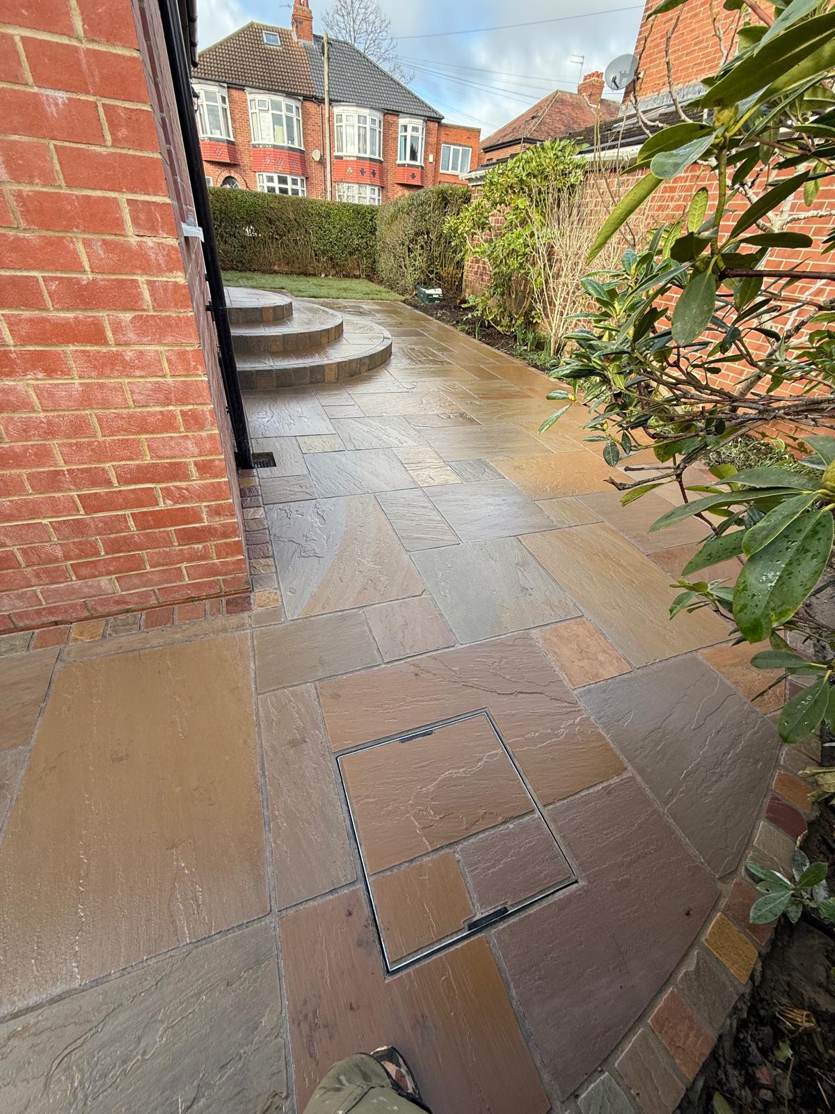 Buff sandstone side path with a recessed cover infilled to match and curved steps beyond — The Vale Company