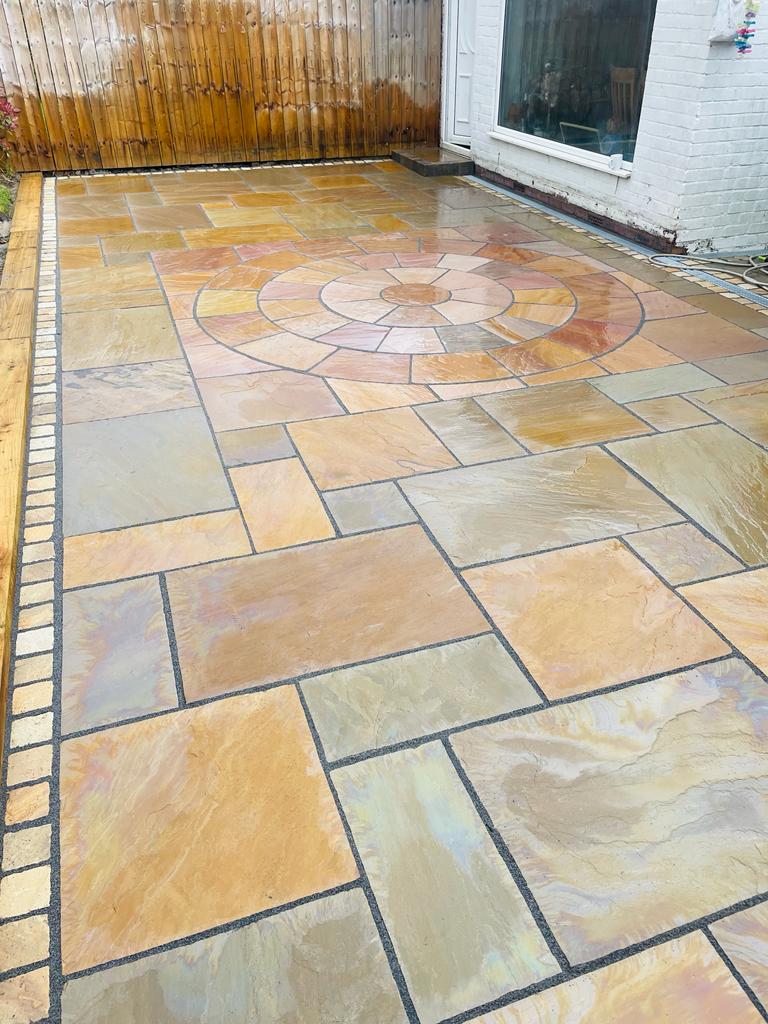 Autumn sandstone patio with a circle feature and a buff sett border along the edge — The Vale Company