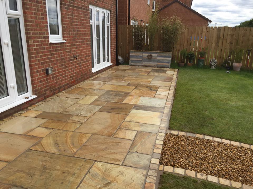 Buff Indian sandstone patio with a sett border running alongside a gravel bed — The Vale Company