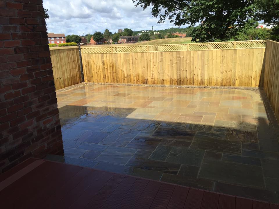 Wet autumn Indian sandstone raised patio finished up to a new fence line — The Vale Company