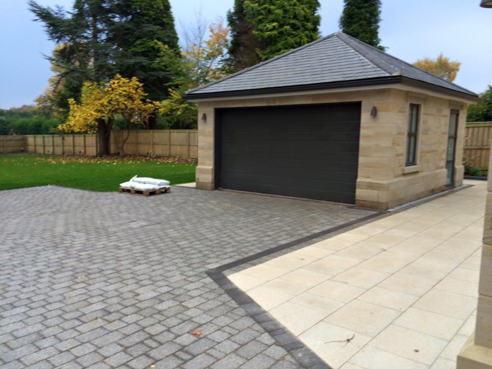 Silver grey tumbled block paved driveway running full width to a double garage — The Vale Company