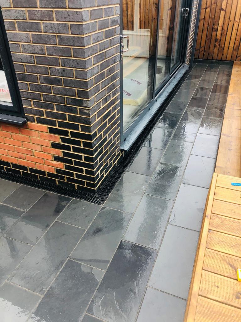 Dark slate paving threshold at a bi-fold door with a gravel drainage strip — The Vale Company