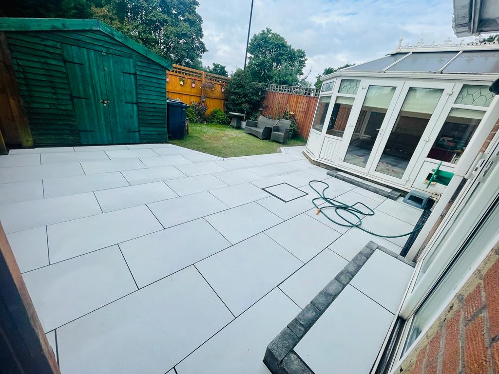 Bright white porcelain terrace with a charcoal block step at a conservatory and a recessed cover — The Vale Company